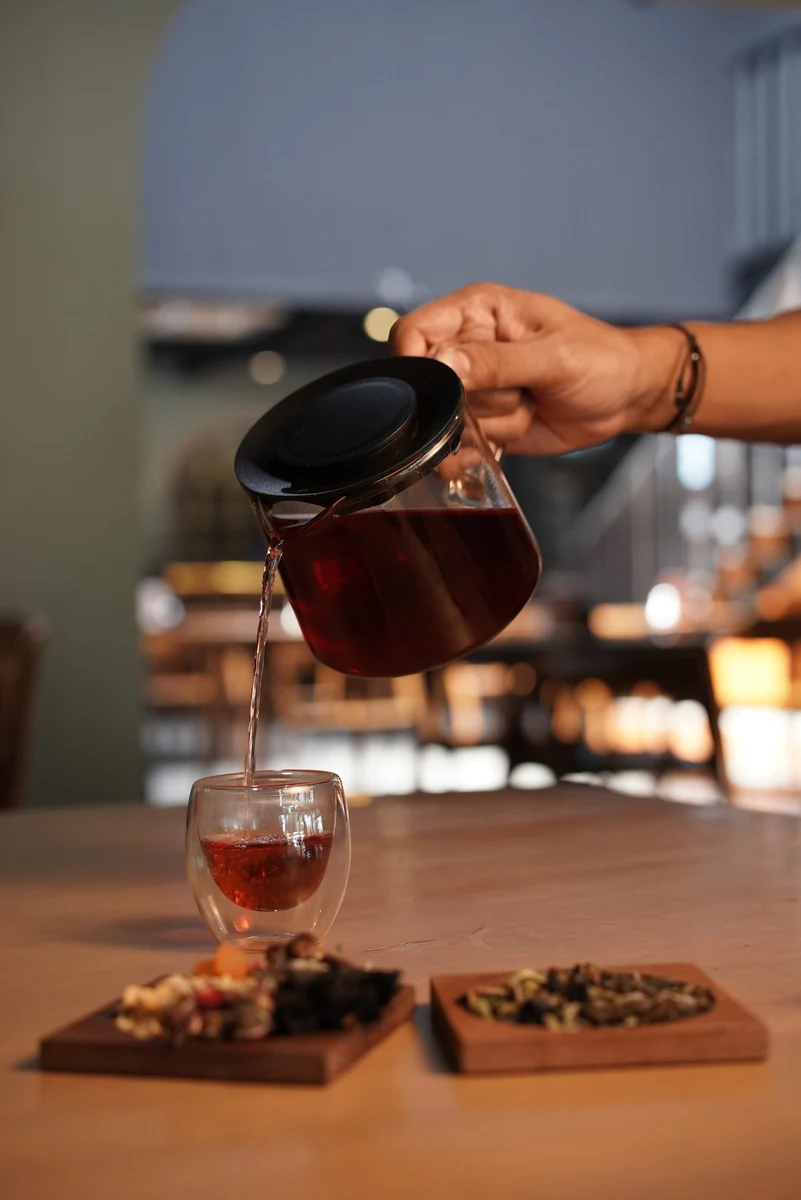 Barista Bosscha Space menuang seduhan teh merah ke dalam gelas kaca